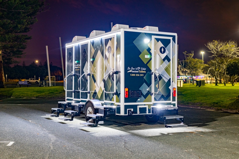 Mobile bathroom trailers parked in an evening setting with street lights