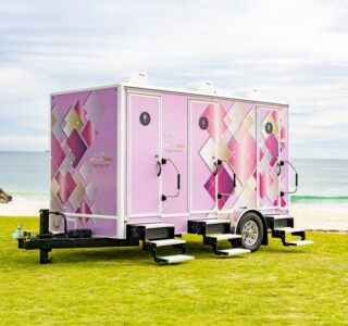 Pink mobile bathroom trailer on grass by the beach
