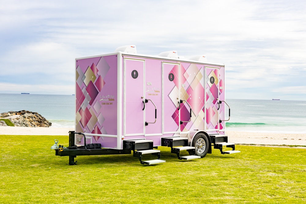 Pink mobile bathroom trailer on grass by the beach