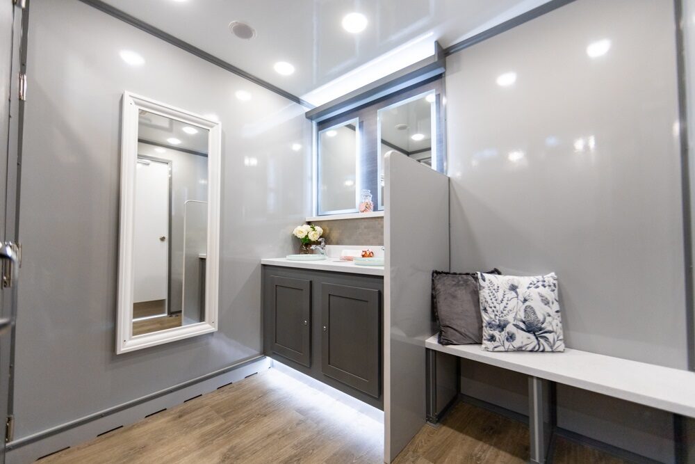 Interior of a luxury portable toilet with a vanity, mirror, and seating area