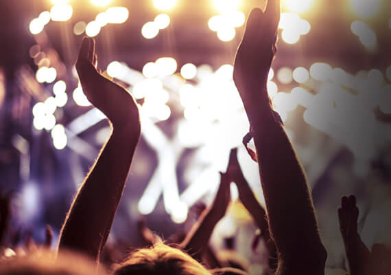 Crowd cheering with raised hands at a concert under bright stage lights. (1)