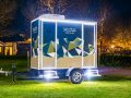 Illuminated mobile bathroom trailer at night in a park setting