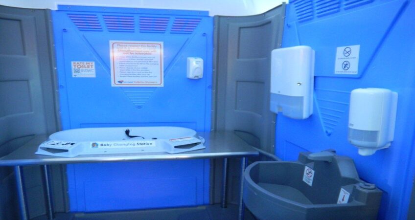 Interior view of a portable toilet equipped with baby changing station and hygiene facilities.